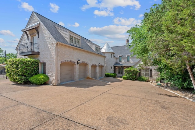 view of front of property featuring a balcony, stone siding, a shingled roof, concrete driveway, and an attached garage