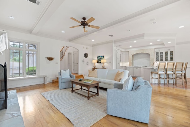 living room with visible vents, arched walkways, light wood-type flooring, beamed ceiling, and ornamental molding