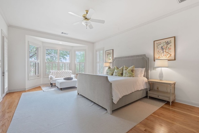 bedroom featuring crown molding, baseboards, light wood-type flooring, and visible vents