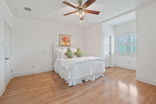 bedroom with baseboards, a ceiling fan, light wood-style flooring, and visible vents