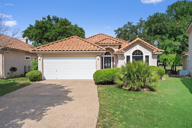 mediterranean / spanish house with an attached garage, driveway, a tile roof, and a front yard