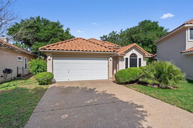 mediterranean / spanish-style home with an attached garage, a front lawn, a tile roof, stucco siding, and driveway
