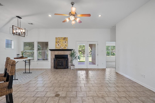 living room with visible vents, baseboards, ceiling fan with notable chandelier, and a tile fireplace