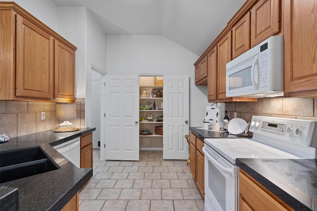 kitchen featuring a sink, lofted ceiling, white appliances, and tasteful backsplash