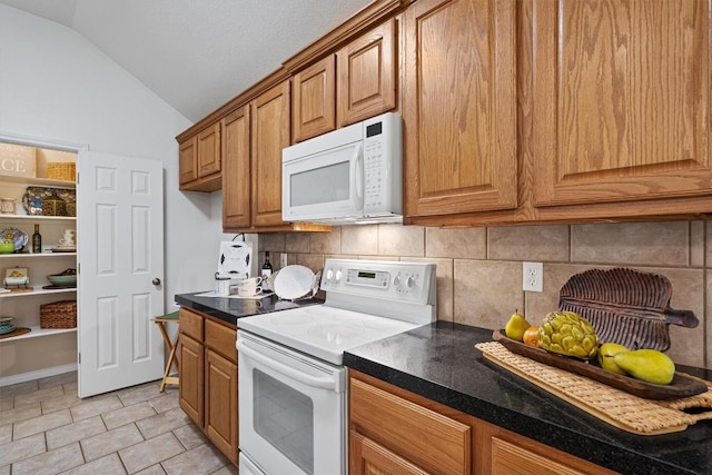 kitchen featuring dark countertops, decorative backsplash, vaulted ceiling, and white appliances