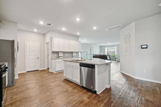 kitchen featuring visible vents, a sink, open floor plan, and stainless steel appliances