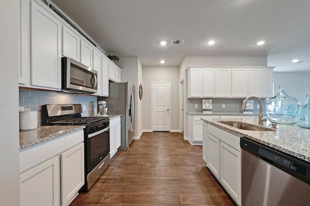 kitchen featuring visible vents, appliances with stainless steel finishes, tasteful backsplash, dark wood finished floors, and a sink