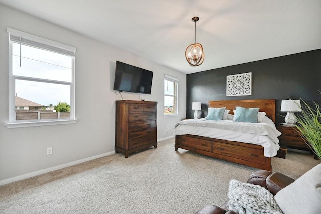 carpeted bedroom featuring an inviting chandelier and baseboards