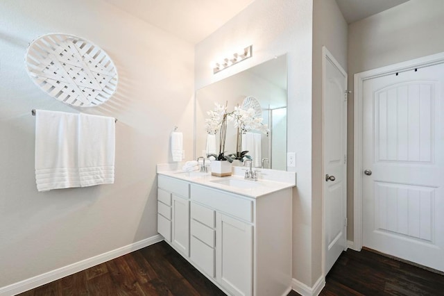 full bathroom featuring double vanity, baseboards, a sink, and wood finished floors