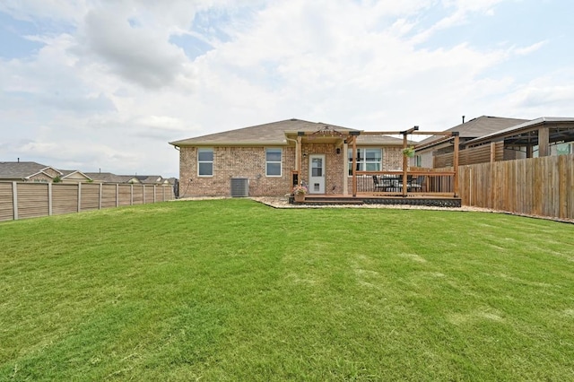 rear view of property featuring a lawn, brick siding, a fenced backyard, and central air condition unit