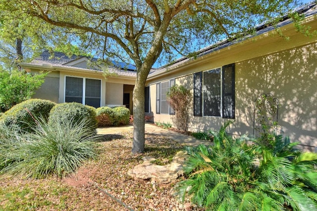 view of home's exterior featuring roof mounted solar panels and stucco siding