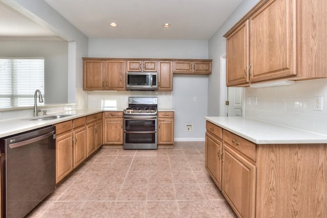 kitchen featuring backsplash, appliances with stainless steel finishes, brown cabinets, a sink, and light countertops
