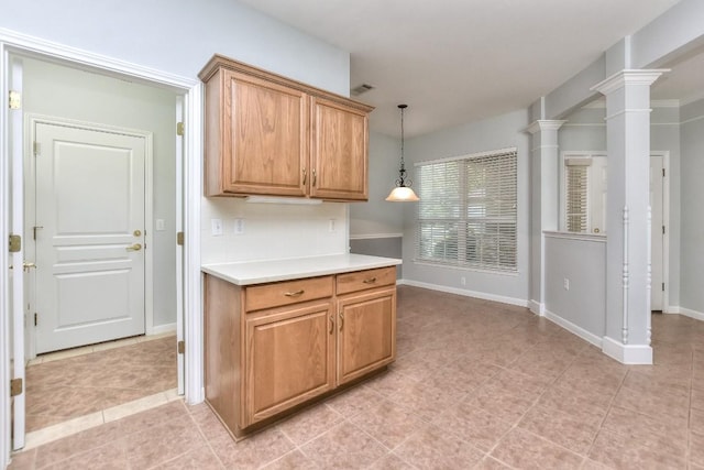 kitchen with light countertops, light tile patterned flooring, decorative light fixtures, and ornate columns