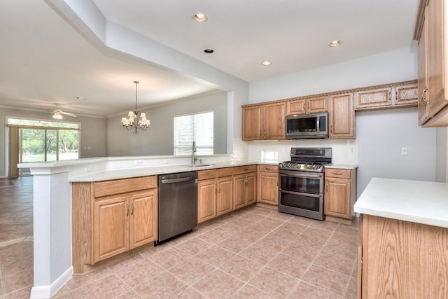 kitchen with pendant lighting, appliances with stainless steel finishes, light countertops, a sink, and a peninsula