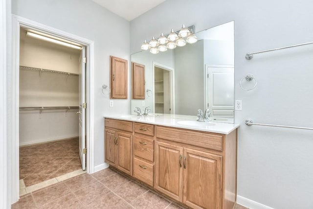 full bathroom featuring double vanity, baseboards, a spacious closet, and a sink