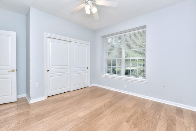 unfurnished bedroom with light wood-type flooring, a ceiling fan, baseboards, and a closet