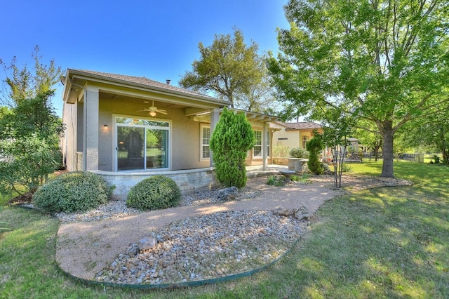 view of front of house featuring a ceiling fan, stucco siding, stone siding, and a front yard