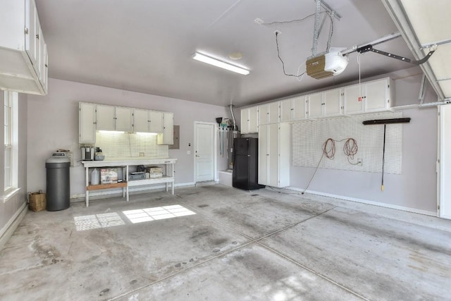garage with baseboards, a garage door opener, electric panel, and freestanding refrigerator