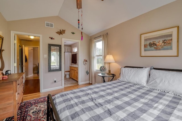 bedroom featuring connected bathroom, light wood-style flooring, baseboards, vaulted ceiling, and visible vents