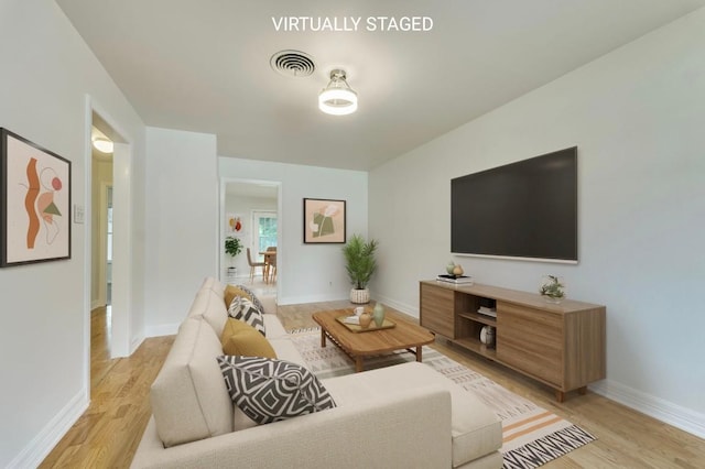 living room with baseboards, light wood-type flooring, and visible vents