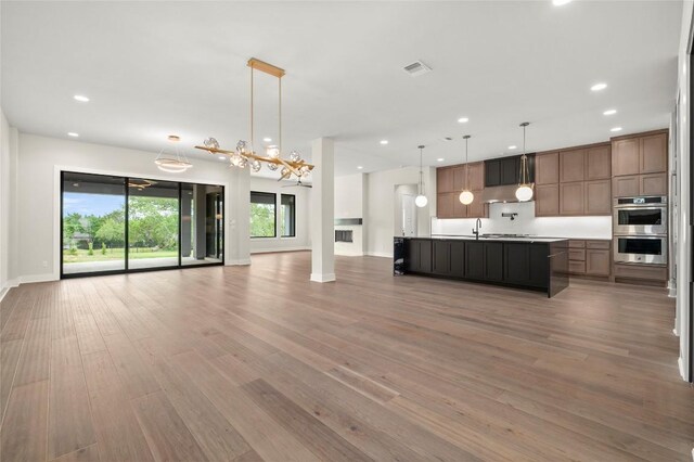 kitchen featuring stainless steel double oven, visible vents, open floor plan, light wood-style floors, and recessed lighting