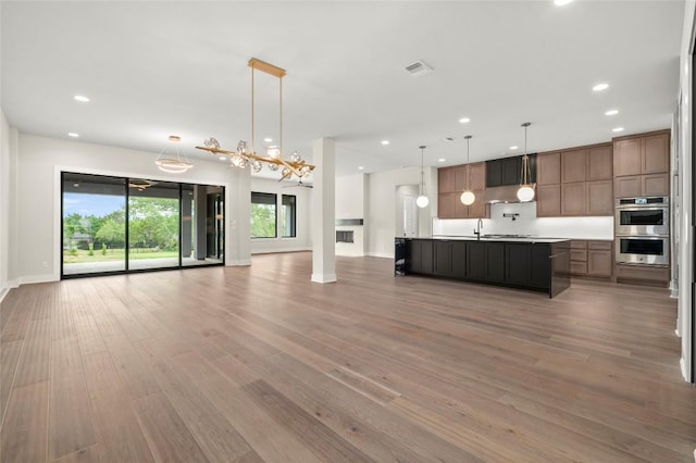 3202 Winding Creek Cv, Austin, TX 78735 - kitchen featuring double oven, open floor plan, light wood-style flooring, recessed lighting, and an island with sink
