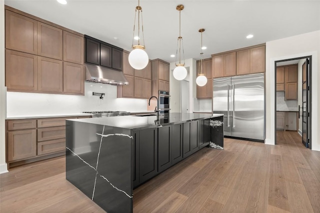 kitchen with a sink, stainless steel appliances, decorative backsplash, under cabinet range hood, and a spacious island
