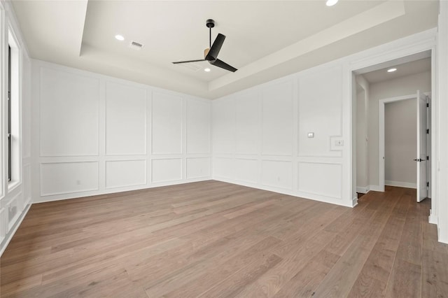 unfurnished room featuring ceiling fan, light wood finished floors, a decorative wall, recessed lighting, and visible vents