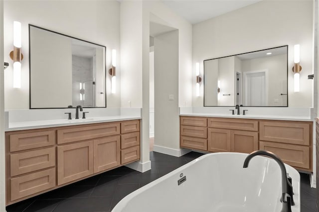 bathroom featuring tile patterned floors, two vanities, a sink, and a freestanding tub