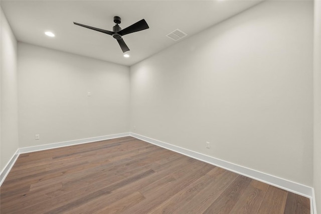 spare room featuring visible vents, a ceiling fan, baseboards, and dark wood-type flooring
