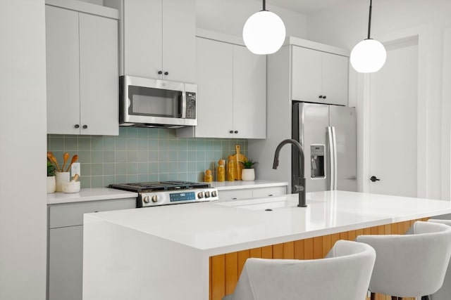6110 Atwood St Unit 1, Austin, TX 78741 - kitchen with a kitchen island with sink, backsplash, a sink, light countertops, and stainless steel appliances