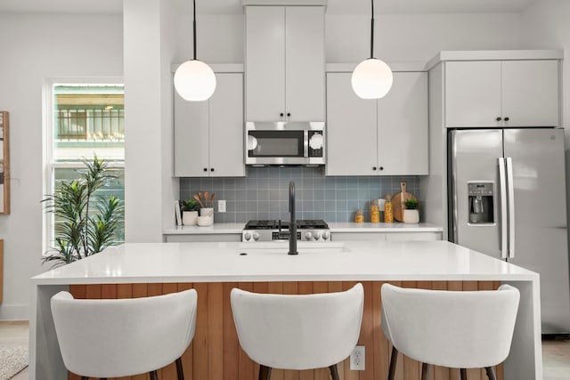 6110 Atwood St Unit 1, Austin, TX 78741 - kitchen with appliances with stainless steel finishes, light countertops, a kitchen island with sink, white cabinetry, and decorative backsplash