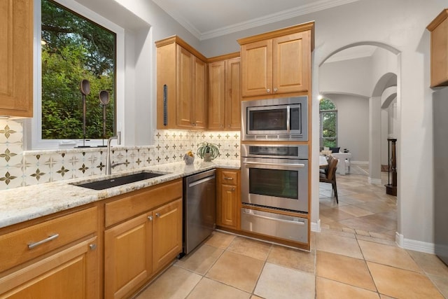 kitchen with appliances with stainless steel finishes, tasteful backsplash, arched walkways, a sink, and a warming drawer