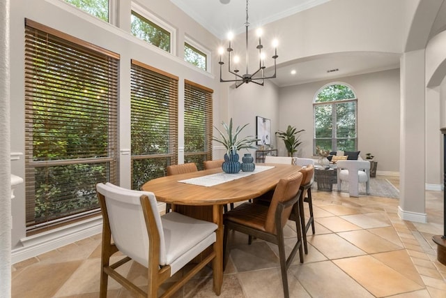 dining room with a towering ceiling, light tile patterned floors, baseboards, a chandelier, and ornamental molding