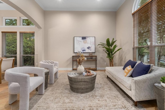 sitting room featuring arched walkways, plenty of natural light, ornamental molding, and baseboards
