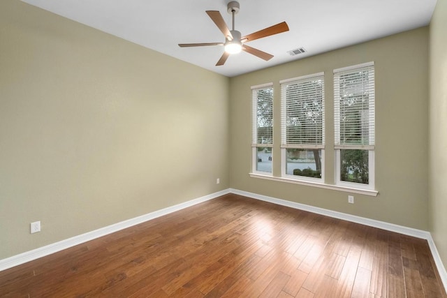 spare room with visible vents, a ceiling fan, baseboards, and dark wood finished floors