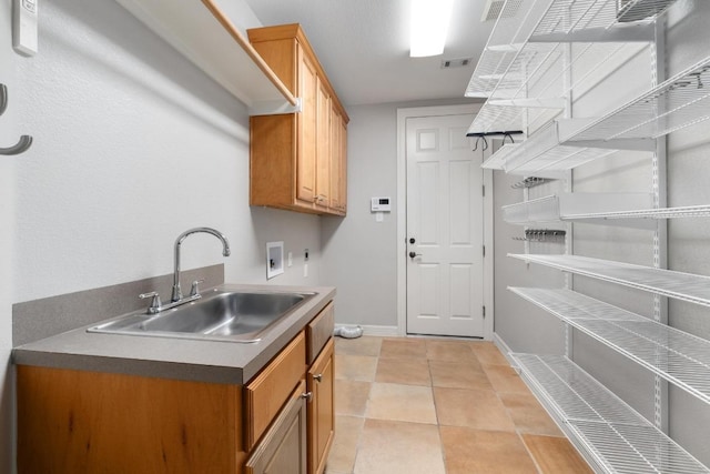 laundry area featuring baseboards, a sink, cabinet space, light tile patterned floors, and washer hookup