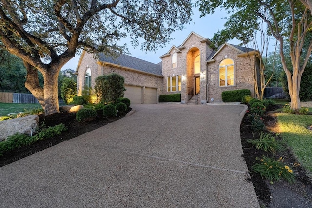 traditional-style home featuring a garage, fence, driveway, and brick siding