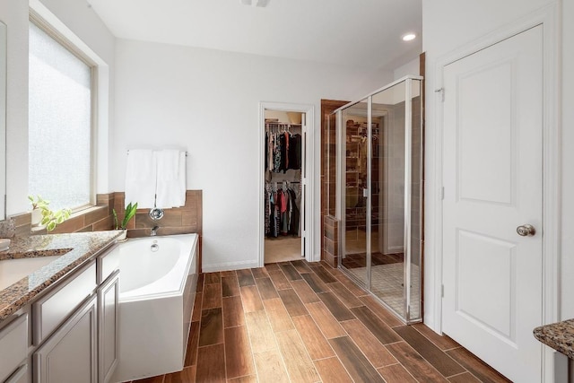 2229 Sauterne Dr, Leander, TX 78641 - full bathroom with vanity, wood tiled floor, a walk in closet, a bath, and a shower stall