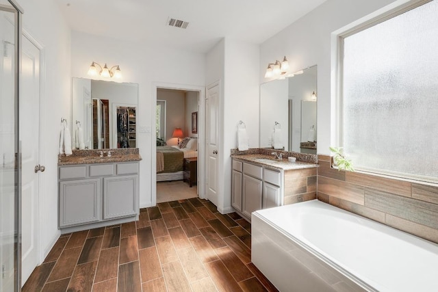 2229 Sauterne Dr, Leander, TX 78641 - full bathroom featuring wood finish floors, a sink, ensuite bath, two vanities, and visible vents
