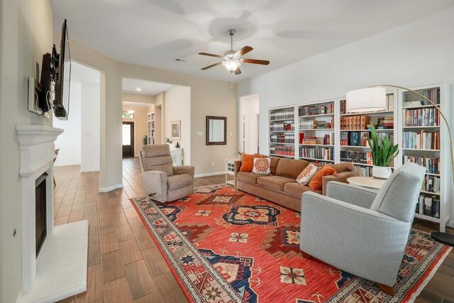 2229 Sauterne Dr, Leander, TX 78641 - living room with visible vents, wood finished floors, baseboards, a fireplace with raised hearth, and a ceiling fan