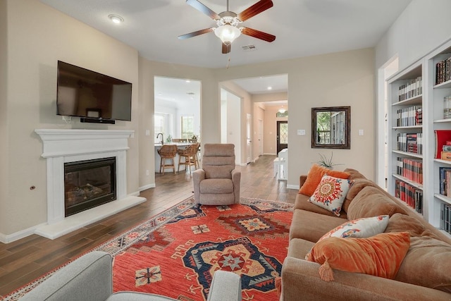 2229 Sauterne Dr, Leander, TX 78641 - living room featuring a glass covered fireplace, baseboards, ceiling fan, and wood finished floors