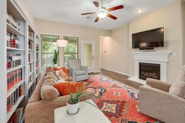 2229 Sauterne Dr, Leander, TX 78641 - living area with visible vents, a glass covered fireplace, wood finished floors, baseboards, and ceiling fan