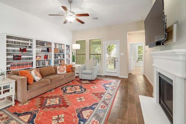 2229 Sauterne Dr, Leander, TX 78641 - living area with ceiling fan, a fireplace with raised hearth, baseboards, wood finished floors, and visible vents