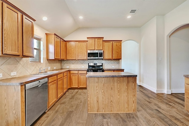 kitchen featuring visible vents, light wood-style floors, arched walkways, a sink, and appliances with stainless steel finishes