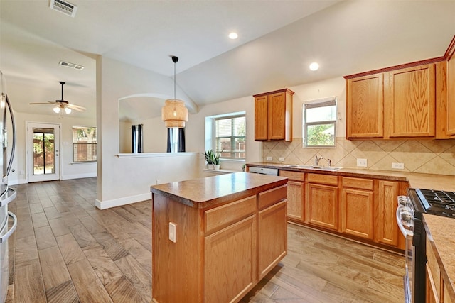 kitchen with visible vents, stainless steel gas stove, tasteful backsplash, a sink, and vaulted ceiling
