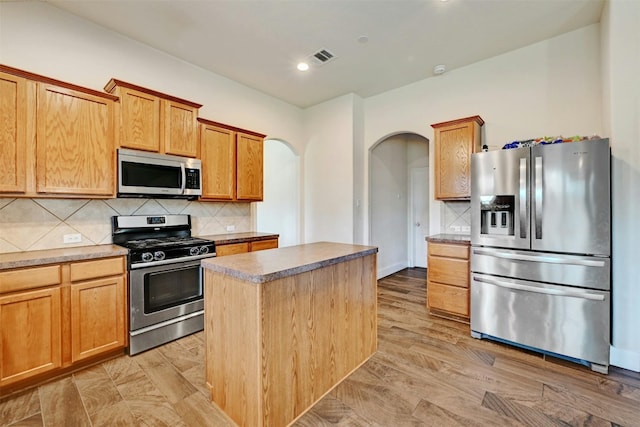 kitchen with a center island, recessed lighting, tasteful backsplash, arched walkways, and stainless steel appliances