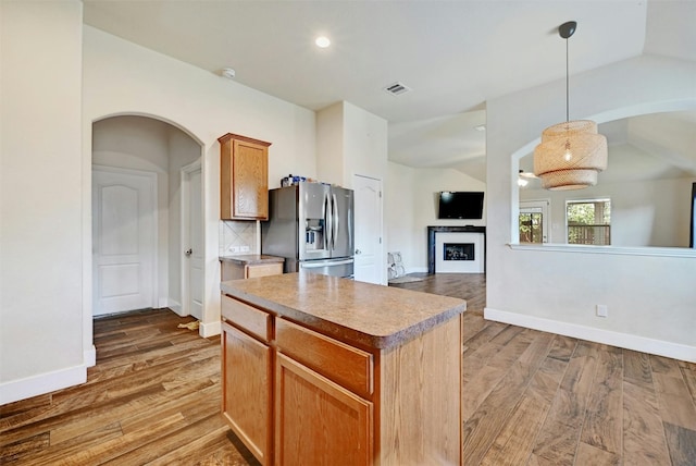 kitchen featuring stainless steel fridge with ice dispenser, a center island, wood finished floors, and visible vents