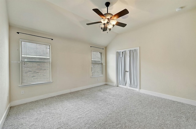 carpeted empty room with baseboards, ceiling fan, and lofted ceiling
