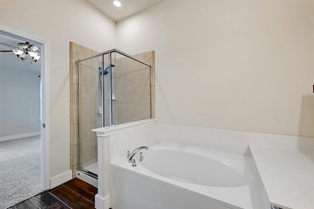 full bathroom featuring a bath, a stall shower, wood finished floors, baseboards, and a baseboard radiator